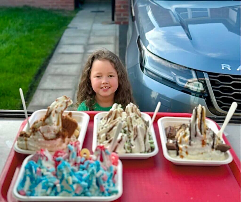 a child similing with her served 4 ice cream trays by shez whippy on the streets of manchester